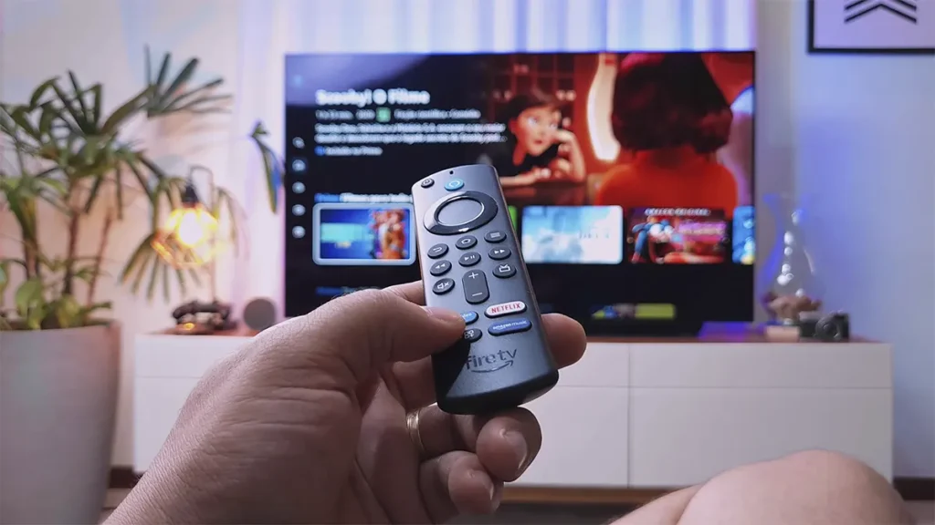 Controle remoto nas mãos de uma pessoa controlando o Fire TV Stick em uma TV.
