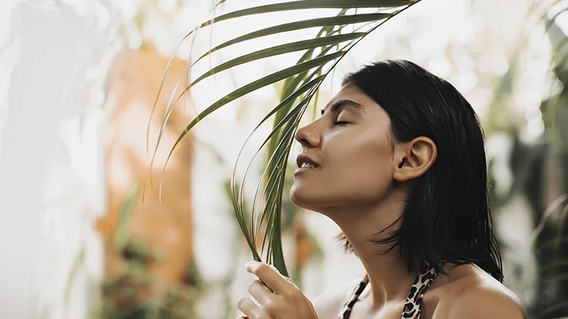 Mulher cheirando uma folha de planta.
