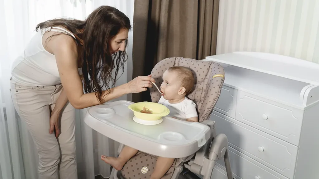 Bebê sentado em uma cadeira de alimentação moderna com bandeja ajustável