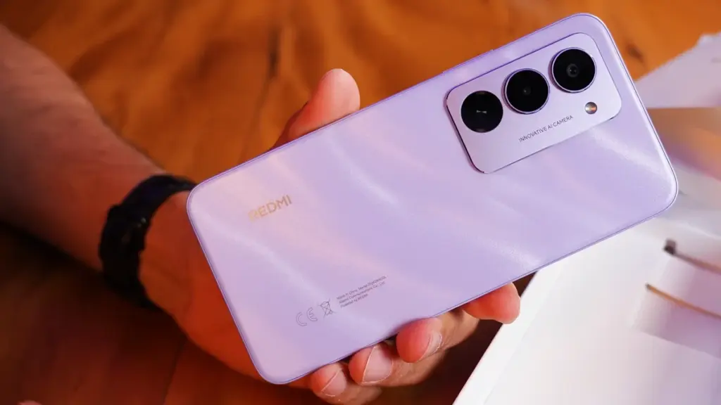 Pessoa segurando um smartphone Redmi 15 4G lilás com três câmeras traseiras.