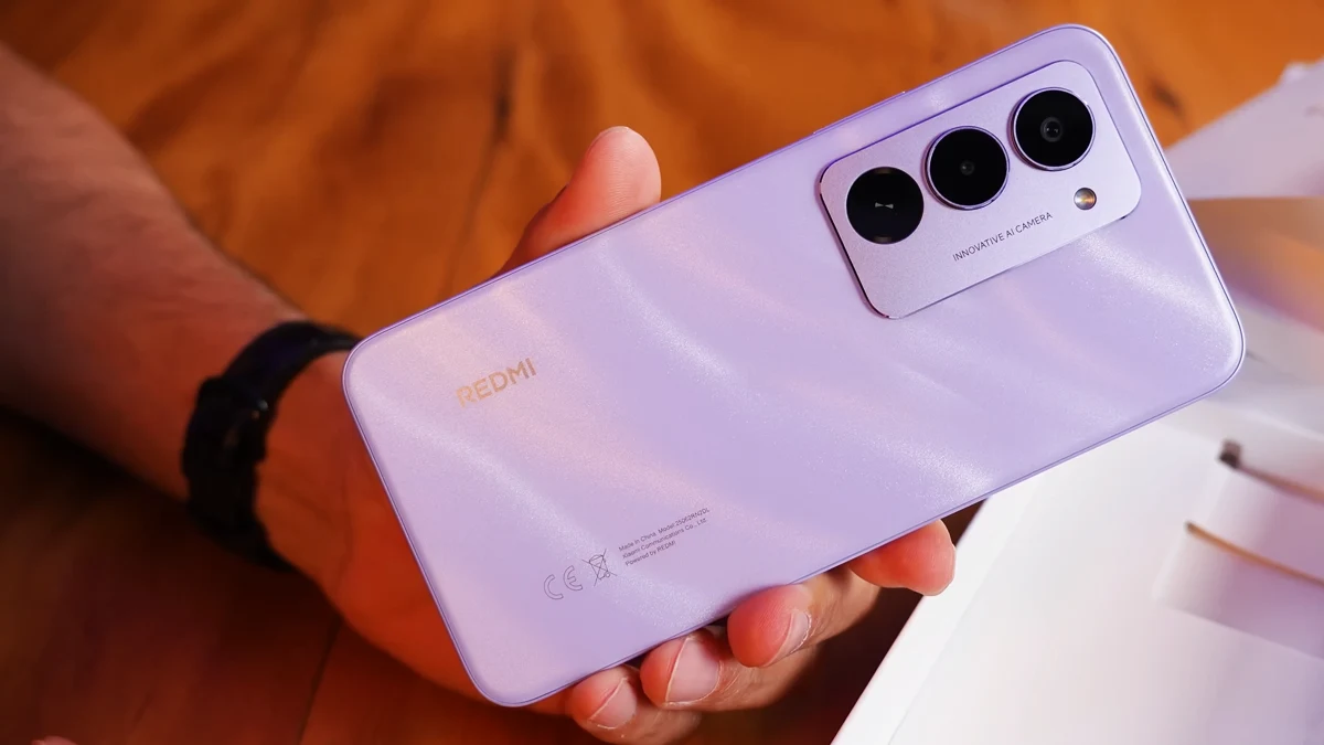 Pessoa segurando um smartphone Redmi 15 4G lilás com três câmeras traseiras.